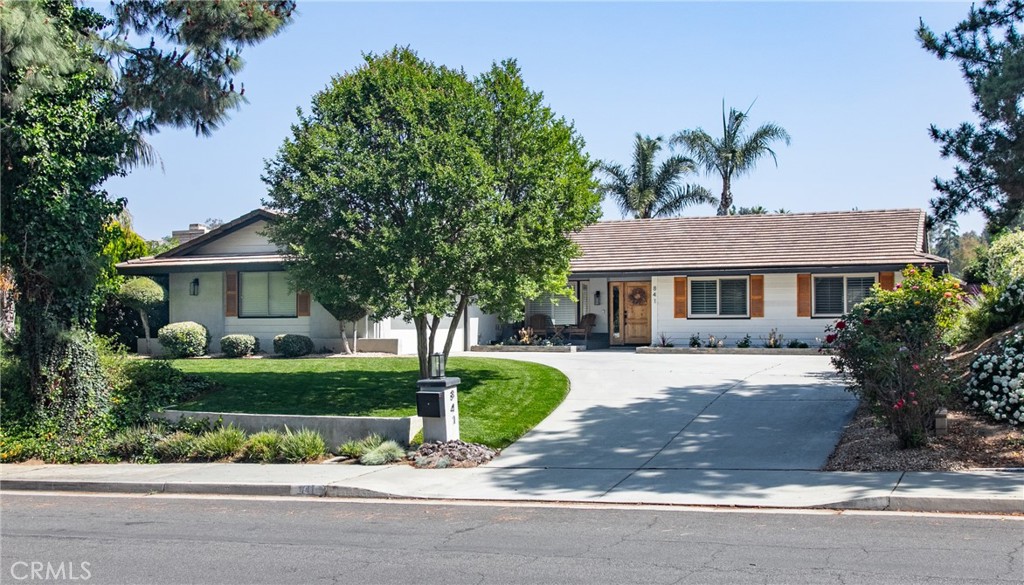 a front view of a house with a garden and trees
