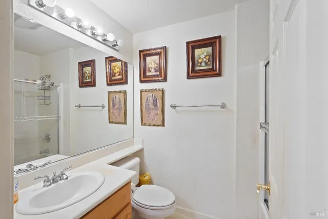 a bathroom with a toilet sink vanity granite and mirror