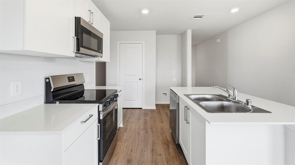3535 Spring Time Street Forney, TX 75126 - Photo 5 of 23 Modern kitchen featuring white cabinetry, stainless steel appliances, light-toned countertops, wood-finish flooring, and recessed lighting