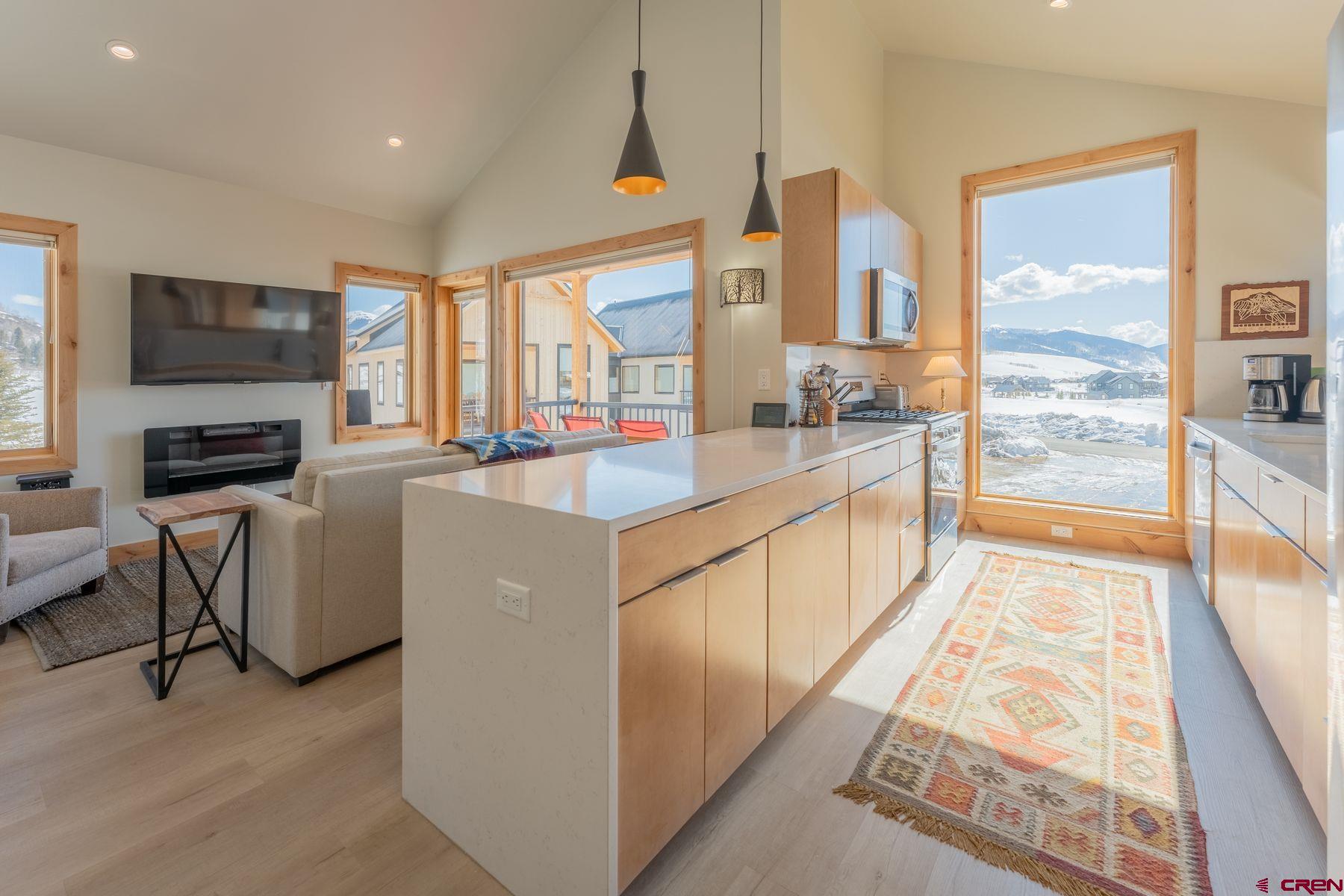 231 Elk Valley Road, Unit 2D Crested Butte, CO 81224 - Photo 8 of 35 a large kitchen with kitchen island granite countertop a stove top oven a sink a dining table and chairs