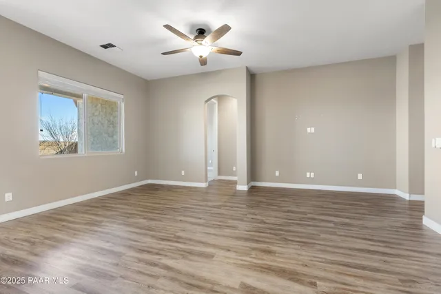 a view of an empty room with a window and wooden floor
