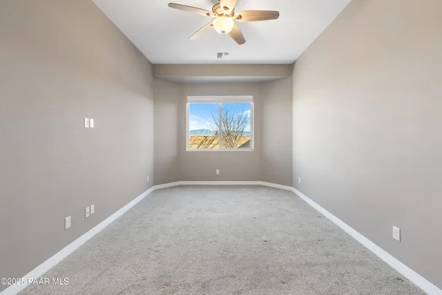 an empty room with a window and a ceiling fan