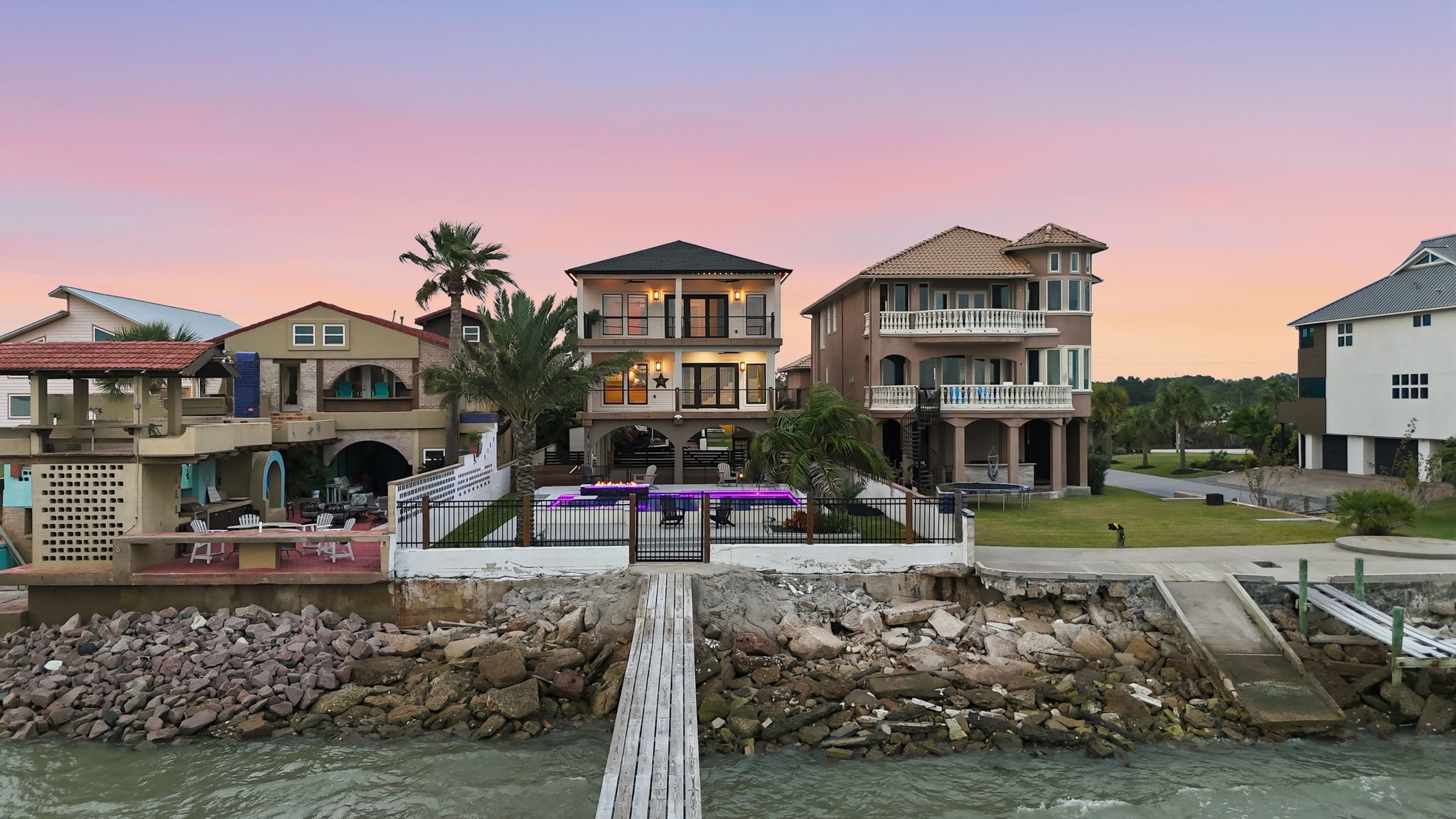 1918 Todville Road Seabrook, TX 77586 - Photo 36 of 41 From the pier, this modern Seabrook bayfront home showcases its full resort-style presence, with a glowing pool, manicured lawn, and second floor balcony are perfectly aligned to capture the sunset sky. The oversized lot, gated seawall, and private water access highlight just how rare and special this waterfront setting truly is.