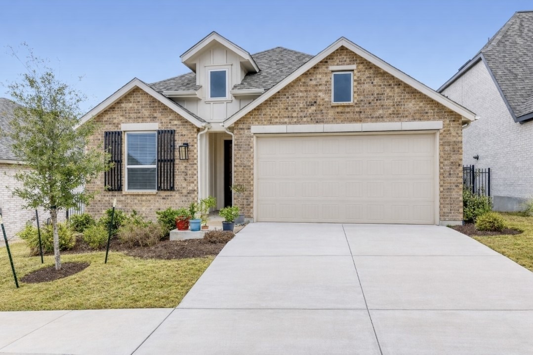 View of front of house featuring concrete driveway, board and batten siding, brick siding, and a front yard