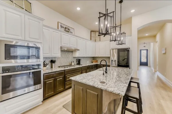 a kitchen with stainless steel appliances kitchen island granite countertop a sink a stove and a refrigerator