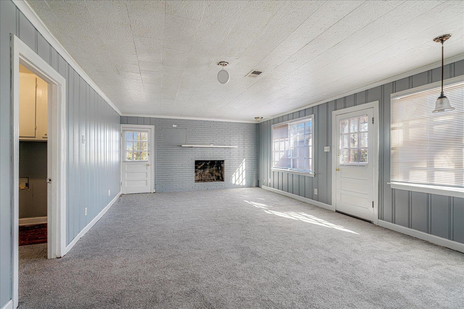 1114 Brownlee Road Memphis, TN 38116 - Photo 14 of 32 Unfurnished living room featuring crown molding, a fireplace, carpet floors, and wood walls