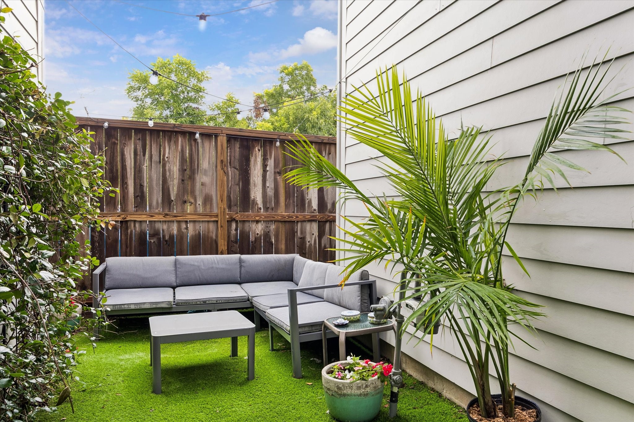 1310 Hussion Street Houston, TX 77003 - Photo 1 of 34 Charming outdoor space with a cozy seating area on artificial grass, surrounded by greenery and privacy fencing, ideal for relaxation or entertaining.