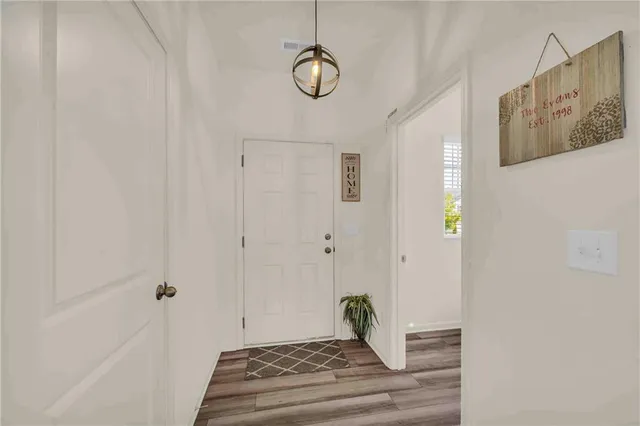 a kitchen with stainless steel appliances a stove a sink dishwasher a refrigerator with white cabinets and wooden floor