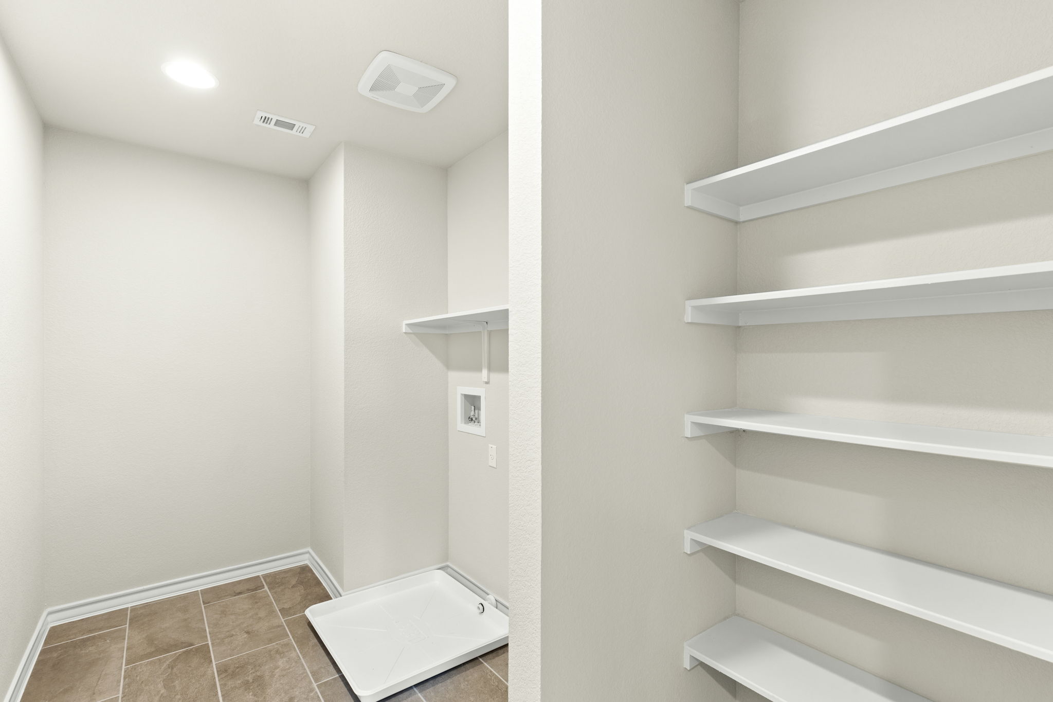 1624 Caballo Blanco Road Austin, TX 78725 - Photo 21 of 27 A functional utility space includes built-in shelving alongside tile floors and laundry connections.