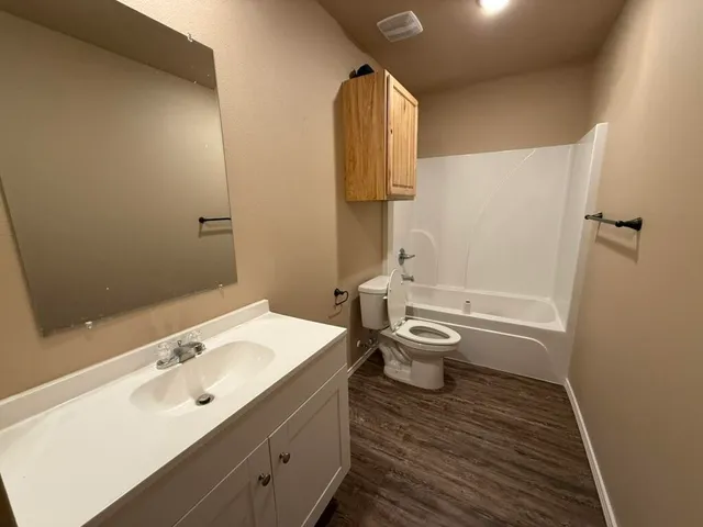 a bathroom with a granite countertop toilet a sink and mirror