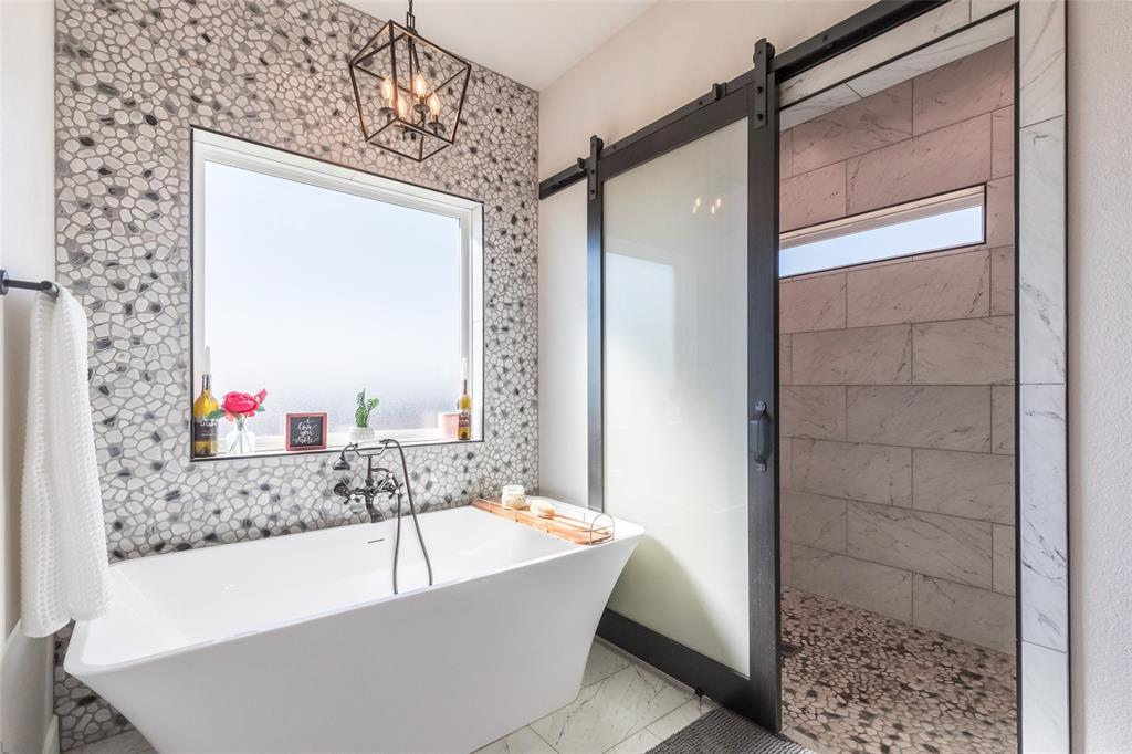 107 Kleingrass Road Abilene, TX 79606 - Photo 15 of 33 Freestanding soaking tub with floor-mounted faucet set against a pebble mosaic accent wall