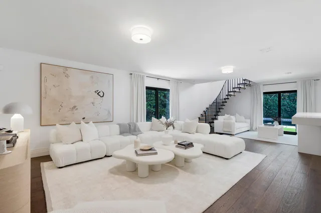 a large white kitchen with a lot of counter space and wooden floor