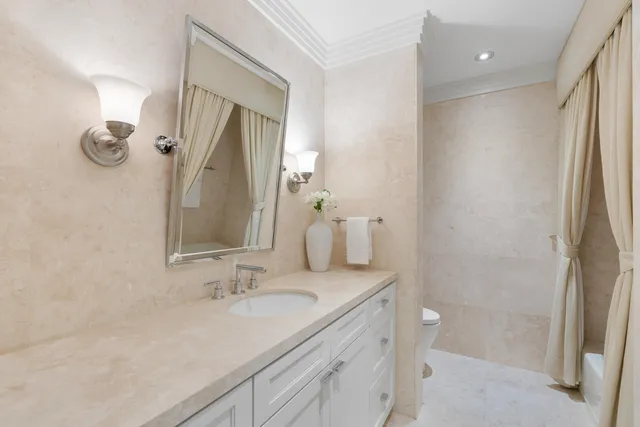 a bathroom with a toilet sink vanity granite and shower