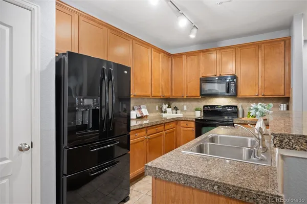 a kitchen with stainless steel appliances granite countertop a sink and a refrigerator