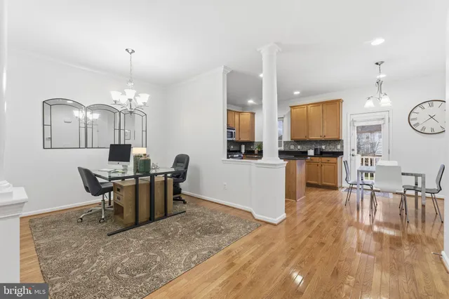 a view of a kitchen with granite countertop a stove a oven a dining table and chairs with wooden floor