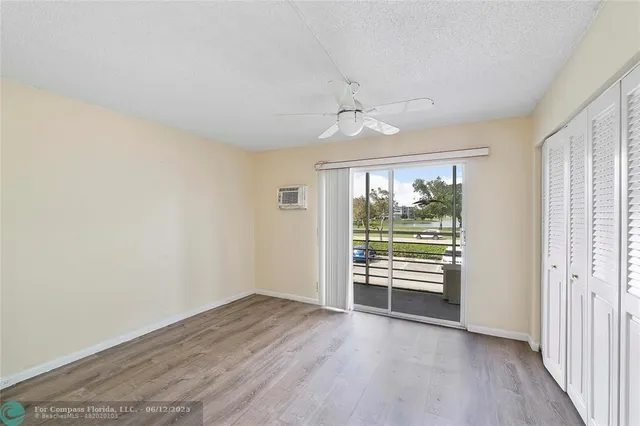 an empty room with wooden floor fan and windows