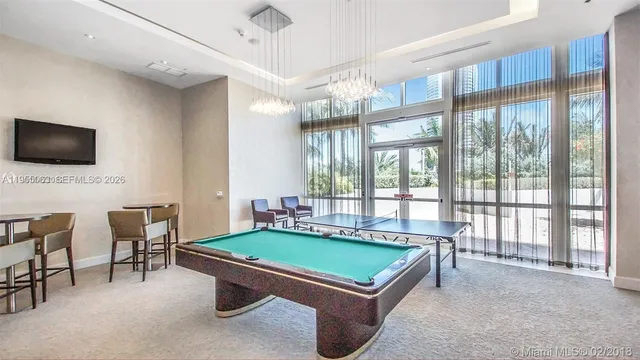 a living room with furniture a flat screen tv and floor to ceiling window