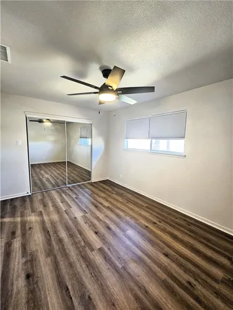 an empty room with wooden floor fan and windows