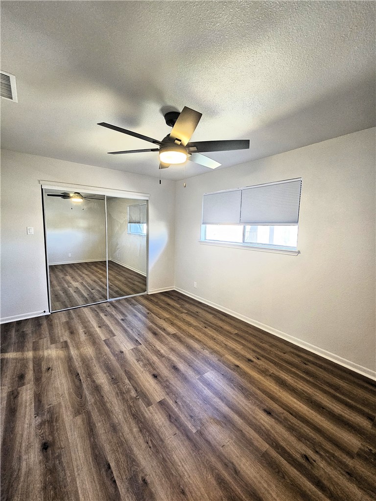 4802 Delwood Street, Unit 3 Corpus Christi, TX 78413 - Photo 13 of 22 an empty room with wooden floor fan and windows