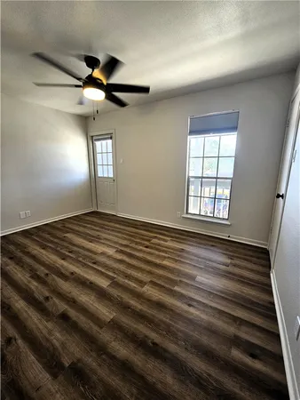 an empty room with wooden floor fan and windows