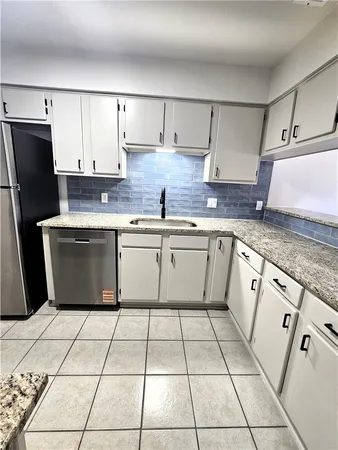 a kitchen with stainless steel appliances granite countertop a sink stove refrigerator and cabinets