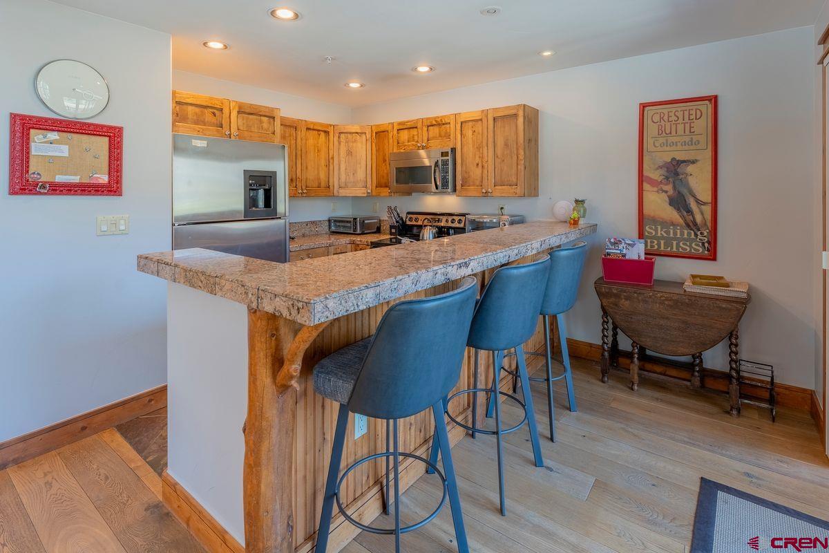 9 Hunter Hill Road, Unit 208 Crested Butte, CO 81225 - Photo 3 of 45 a kitchen with stainless steel appliances granite countertop table chairs sink and wooden floor