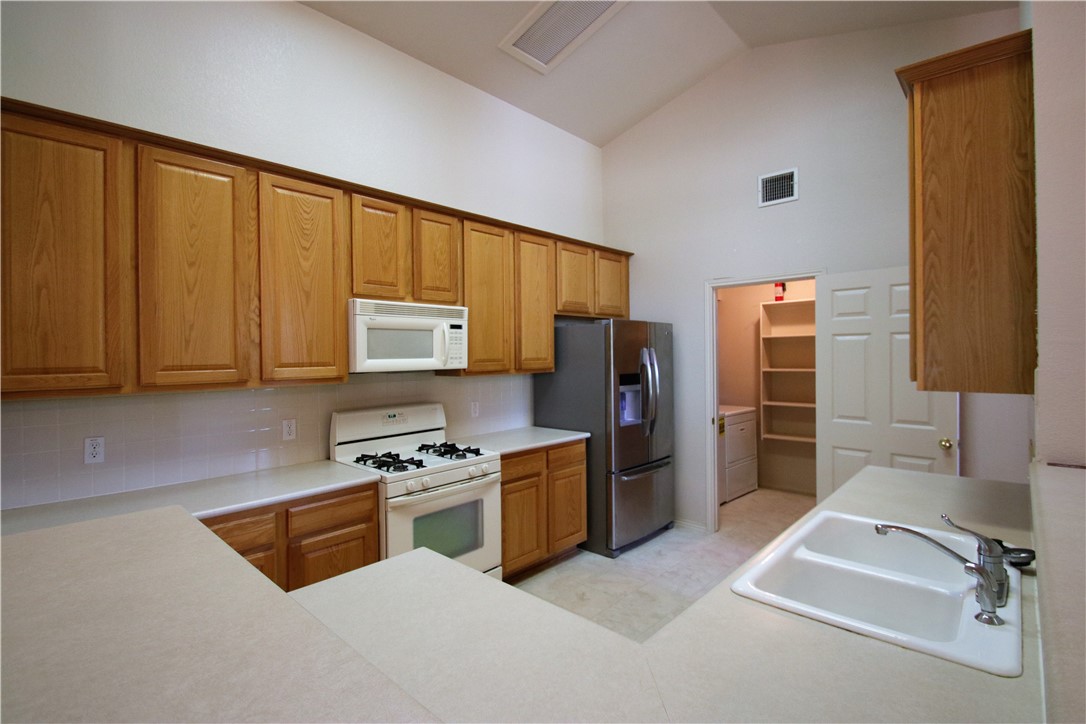 16516 Fowler Mill Cove Austin, TX 78717 - Photo 3 of 27 a kitchen with stainless steel appliances a stove a sink and a refrigerator with wooden cabinets