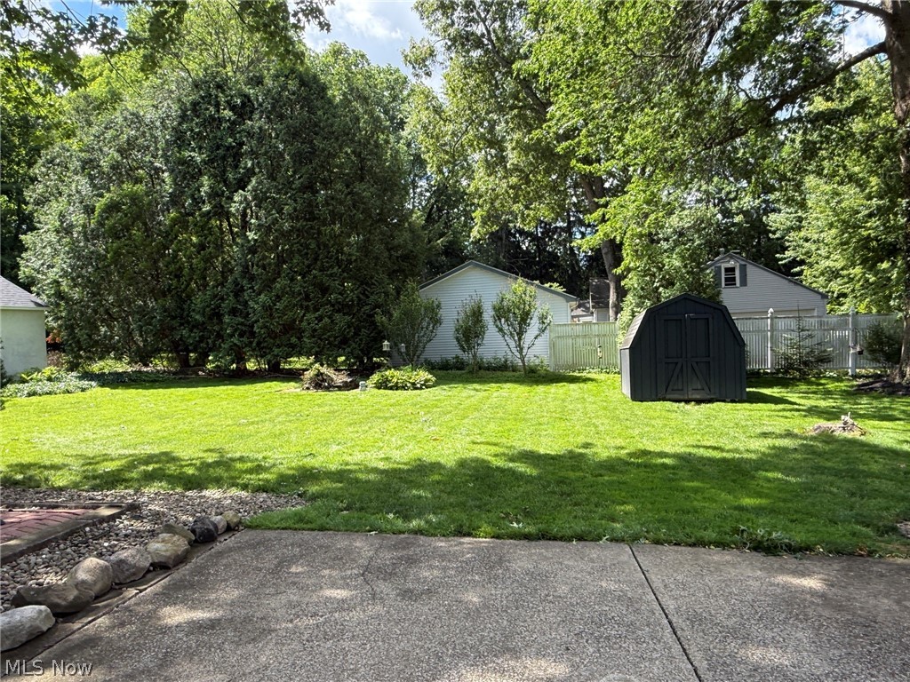 2411 Ridgeview Lane Youngstown, OH 44514 - Photo 36 of 48 Expansive lawn area featuring a dark-toned storage shed, mature perimeter trees, established shrubs, and a concrete patio with a stone border