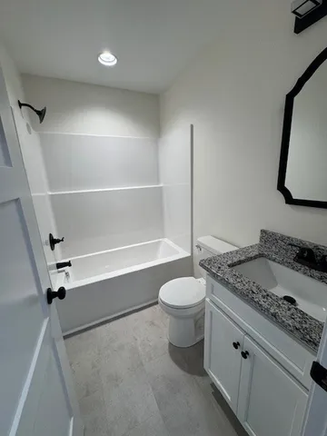 a bathroom with a granite countertop sink mirror vanity and toilet