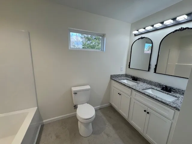a spacious bathroom with a granite countertop toilet a sink and bathtub