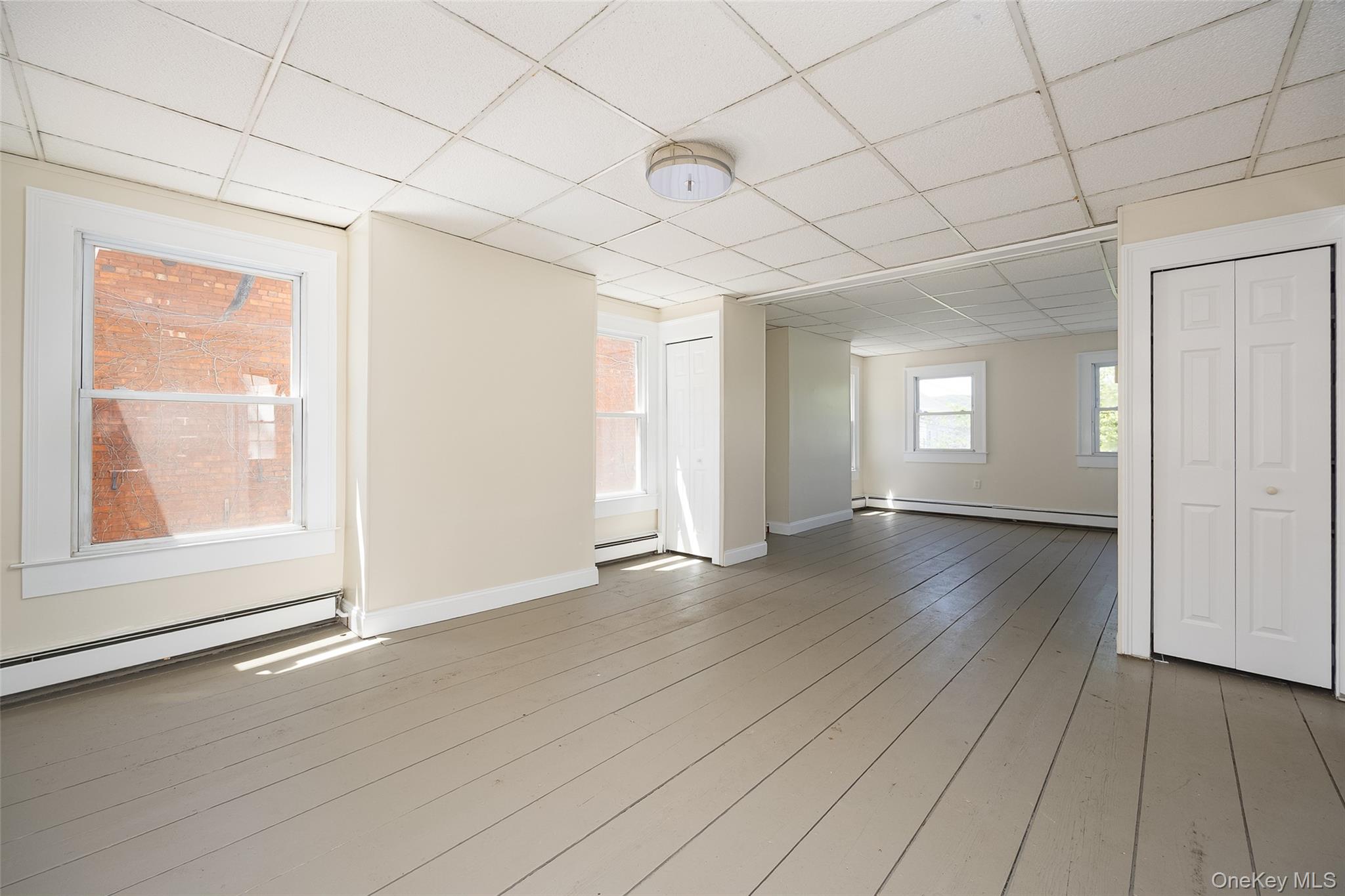 29 Delano Street, Unit 2 Poughkeepsie, NY 12601 - Photo 9 of 16 an empty room with wooden floor and windows with curtains