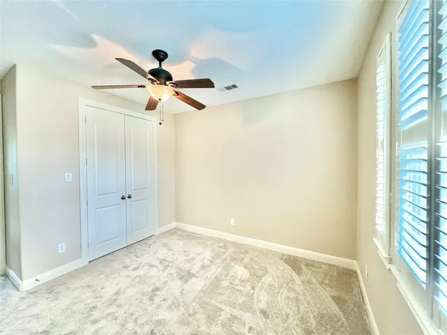 a view of an empty room and window and a ceiling fan