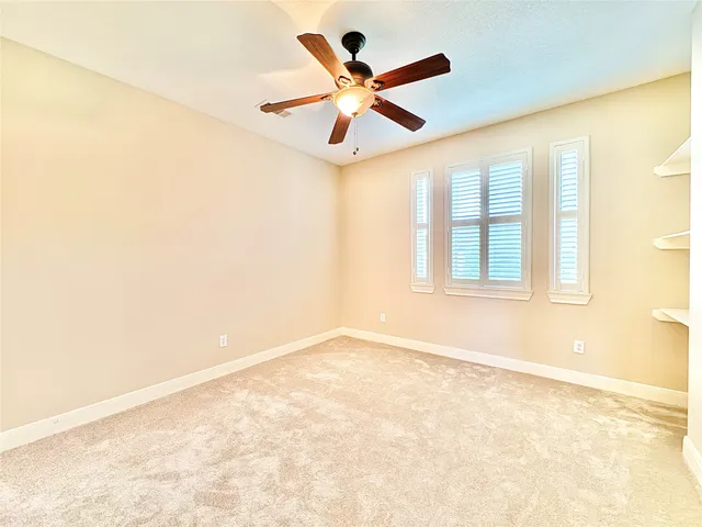 an empty room with ceiling fan and windows