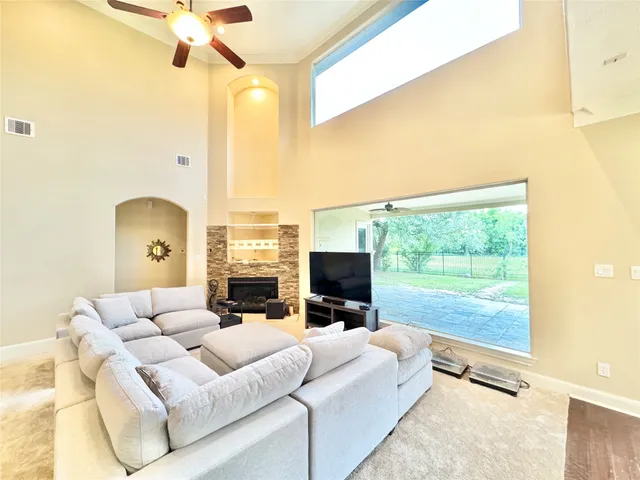 a living room with couches a flat tv screen and a fireplace with wooden floor
