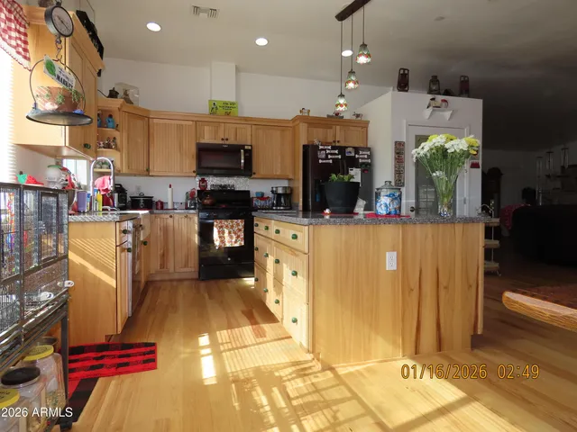 a kitchen with stainless steel appliances kitchen island granite countertop a sink counter space and a view of living room