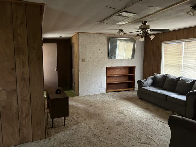 a living room with furniture a ceiling fan and a window