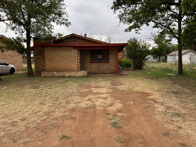 a view of a house with a large tree and a yard