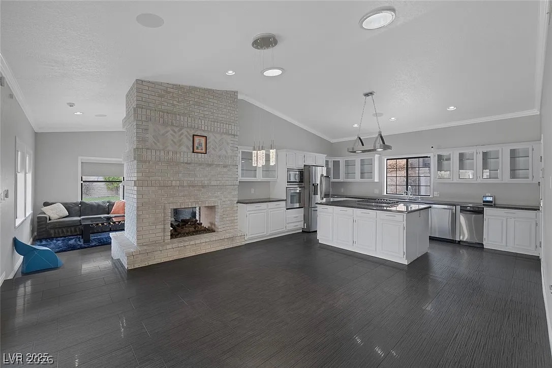 9 Quail Run Road Henderson, NV 89014 - Photo 18 of 57 A striking brick fireplace anchors this open-concept great room with vaulted ceilings and a modern kitchen.