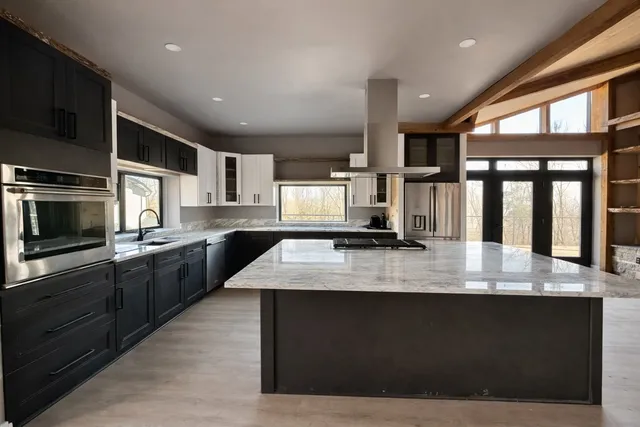 a large kitchen with granite countertop a large counter top stainless steel appliances and cabinets