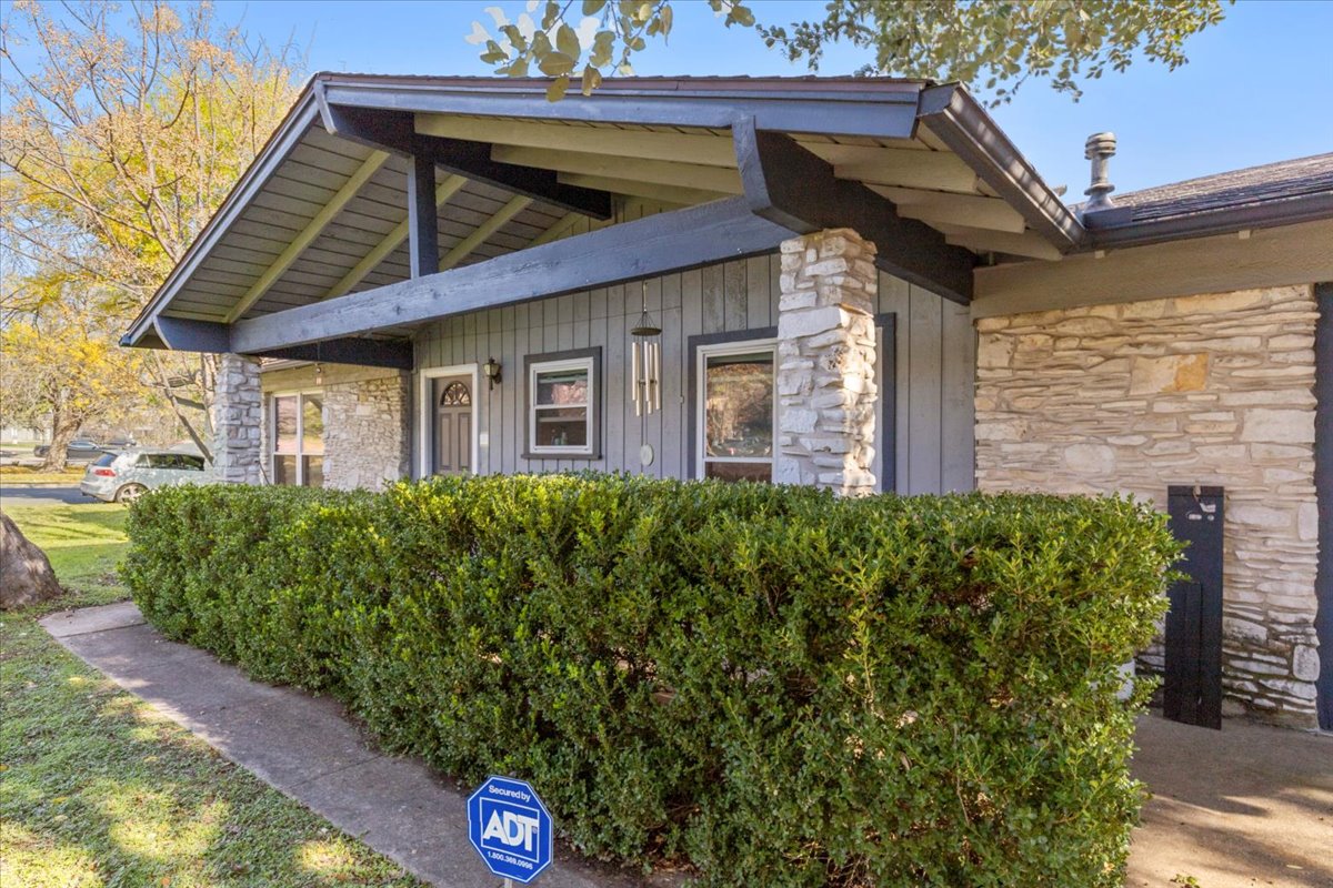 8713 Azalea Trail Austin, TX 78759 - Photo 2 of 13 Stone and siding create an inviting facade, framed by a manicured hedge and mature tree.