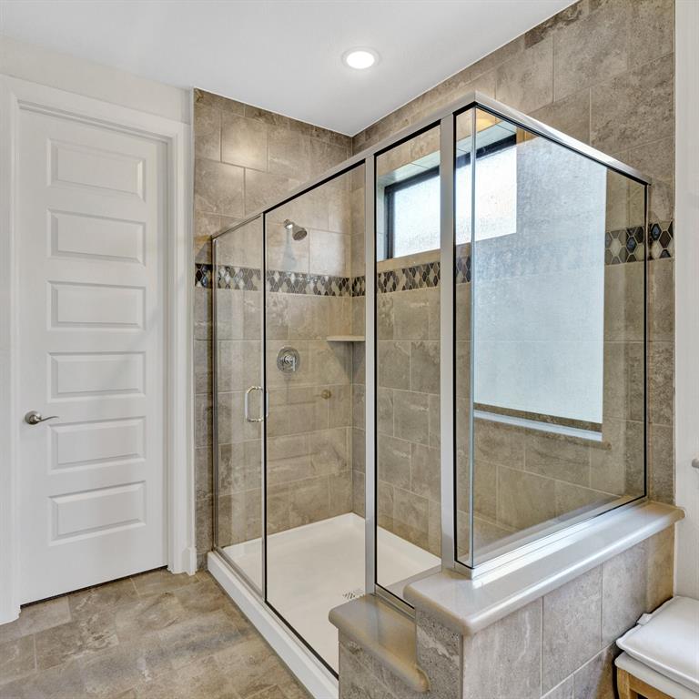 602 Winners Circle Rowlett, TX 75088 - Photo 20 of 35 Master bathroom, ensuite featuring a glass-enclosed shower with full tile surround, integrated shower niche, and mosaic tile accent band