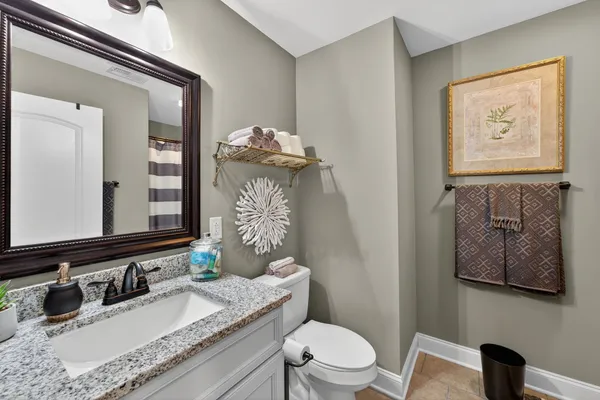 a bathroom with a granite countertop sink mirror vanity and toilet