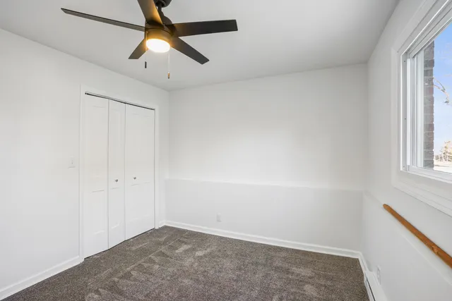 an empty room with windows and fan