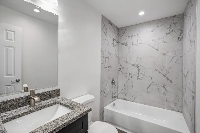 a bathroom with a granite countertop sink a toilet and bathtub