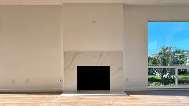 an empty room with wooden floor fireplace and windows