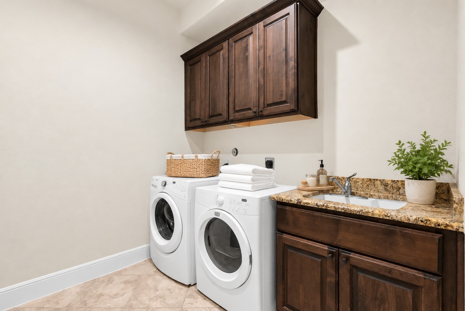 4022 Sabine Valley Trail Spring, TX 77386 - Photo 23 of 46 Laundry room with granite countertop and a sink, and ample storage with upper and lower wood cabinets. The space is bright and functional, ideal for efficient laundry tasks.
