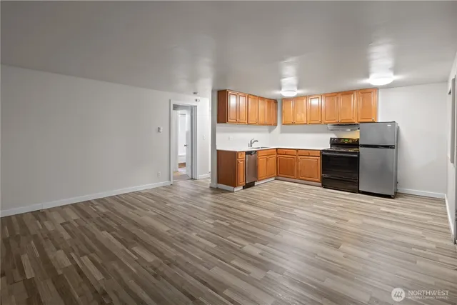 a view of kitchen with stainless steel appliances wooden floor and a refrigerator