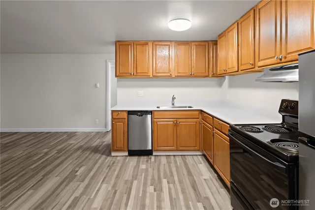 a kitchen with a sink a stove cabinets and wooden floor
