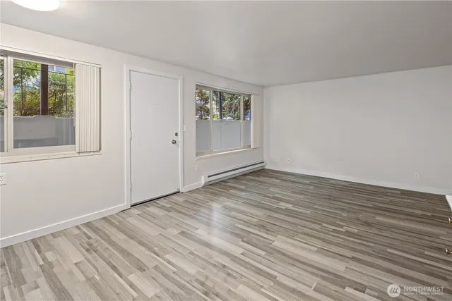 a view of an empty room with wooden floor and a window