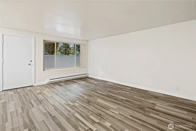 a view of an empty room with wooden floor and a window